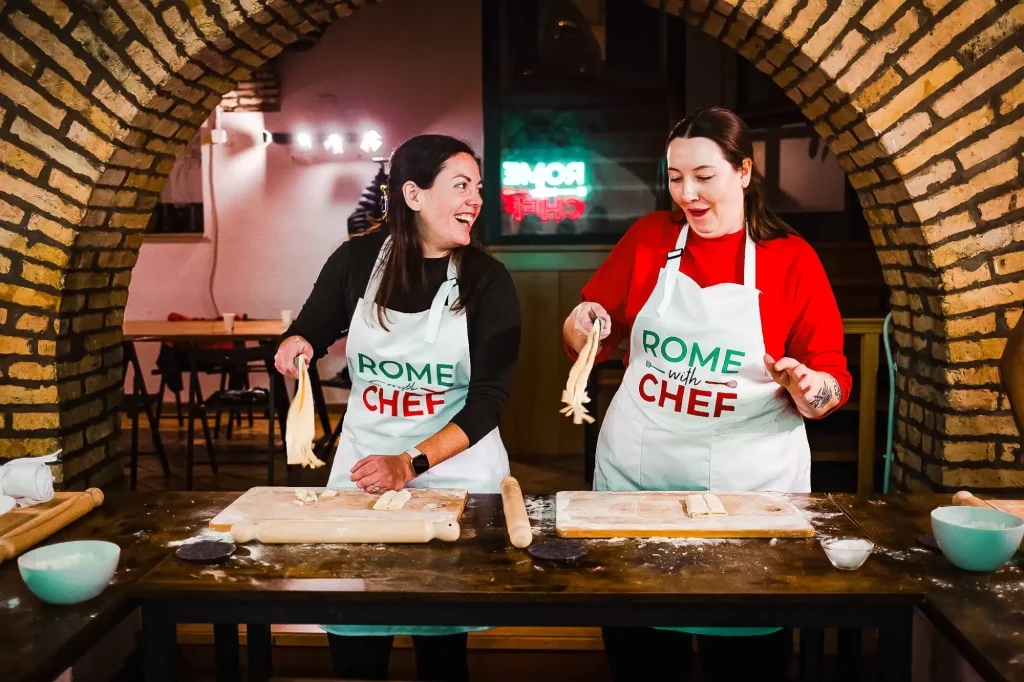 Young women making freshly prepared homemade pasta on a wooden board during a Pasta and Tiramisu Cooking Class