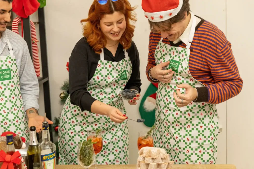 Woman with red hair adding fresh blueberries to orange aperitif cocktails garnished with rosemary during a beverage preparation class