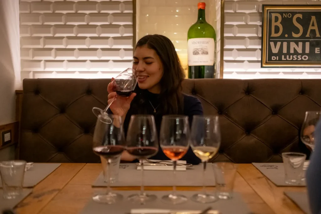 A woman smiling while participating in a wine tasting with four different glasses of wine."
