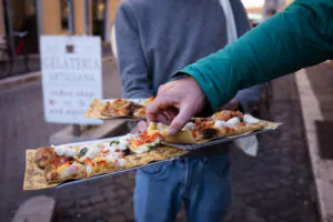 Taking a slice of traditional Roman-style pizza, one of the more typical types of Italian pizza, on our Trastevere Food Tour