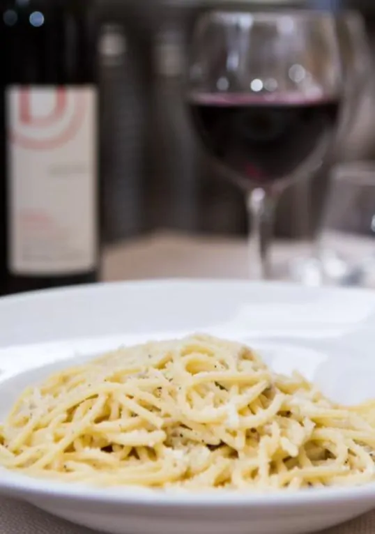 Our easy cacio e pepe recipe with a glass of Roman Cesene wine in the background 
